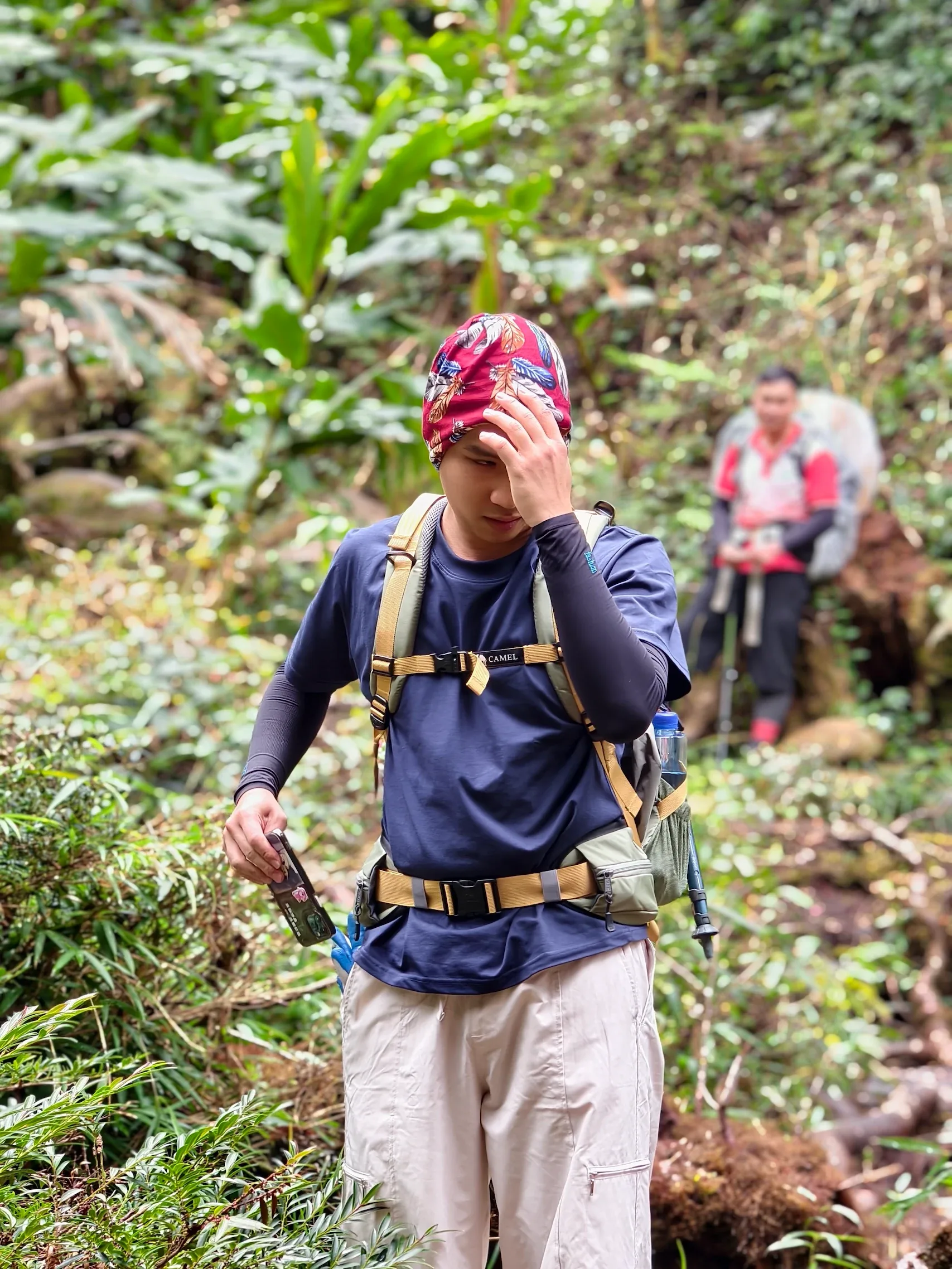 Nữ du khách quấn khăn đỏ cầm gậy trekking trên đường rừng
