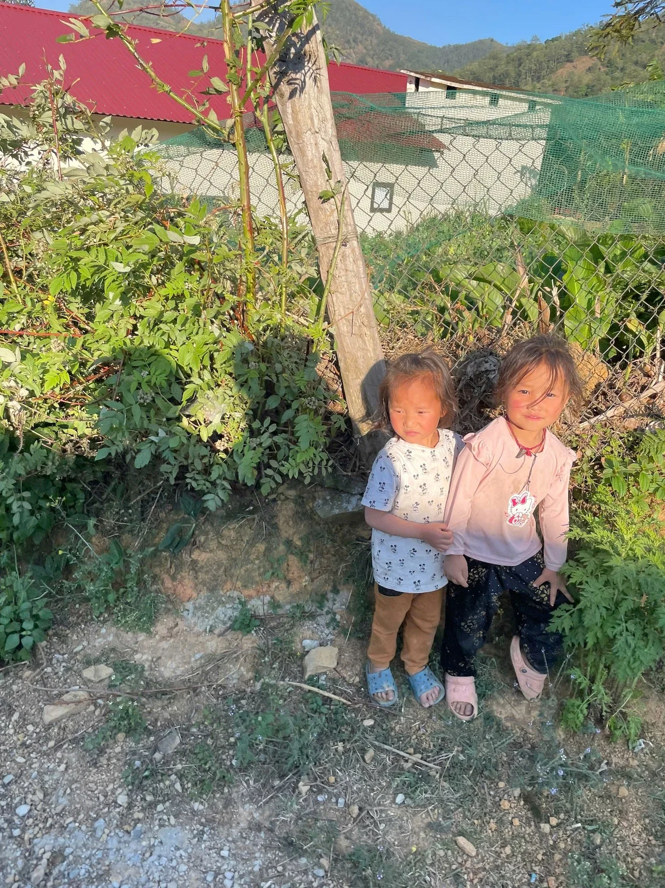 Hai em nhỏ đứng bên lối đi trong bản vùng cao