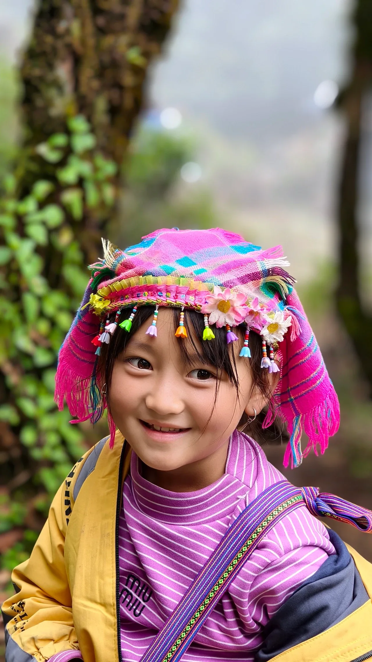 Bé gái mặc trang phục thổ cẩm nhiều màu mỉm cười