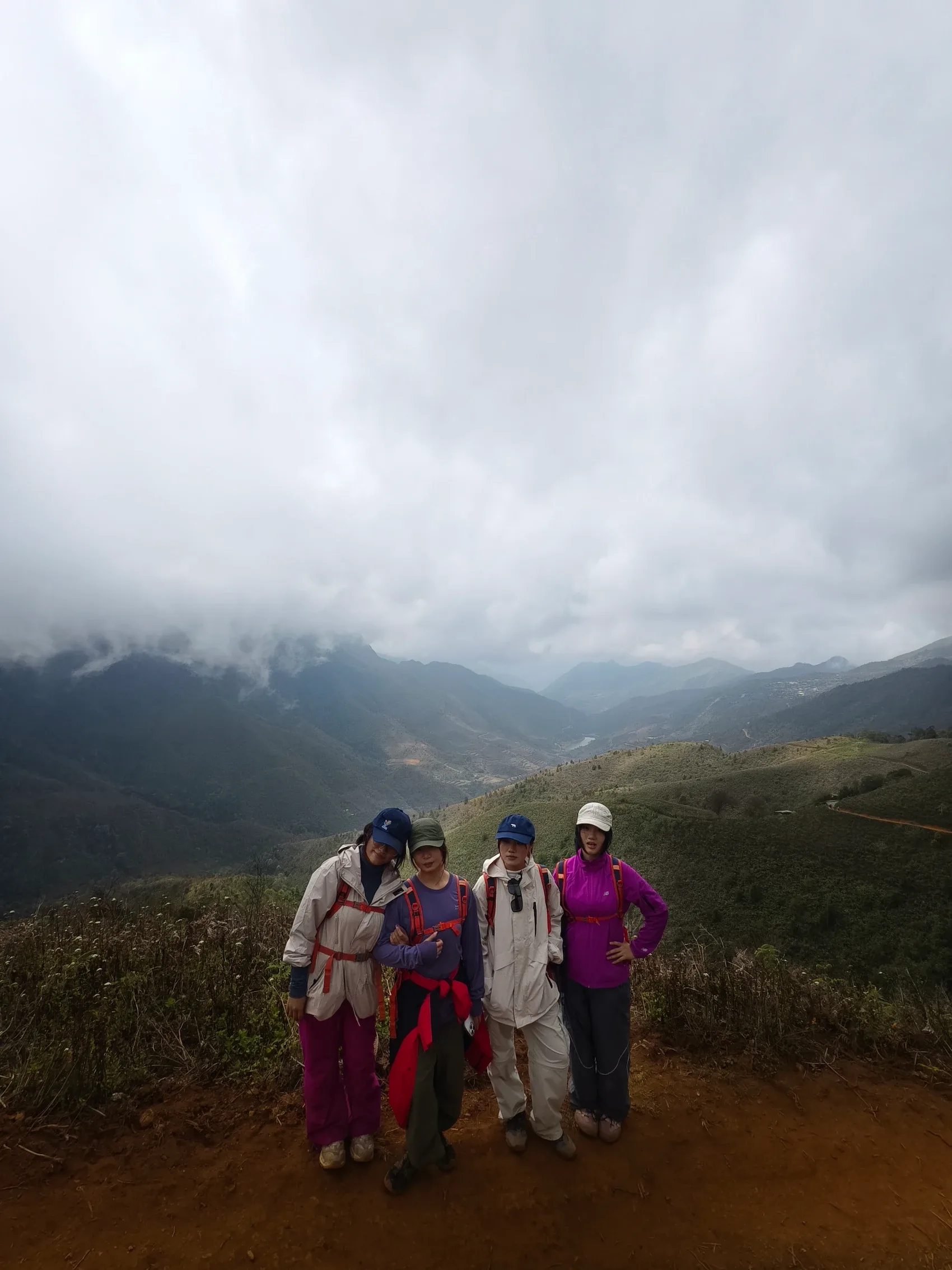 Nhóm bốn người trekking chụp ảnh trên đường núi nhiều mây