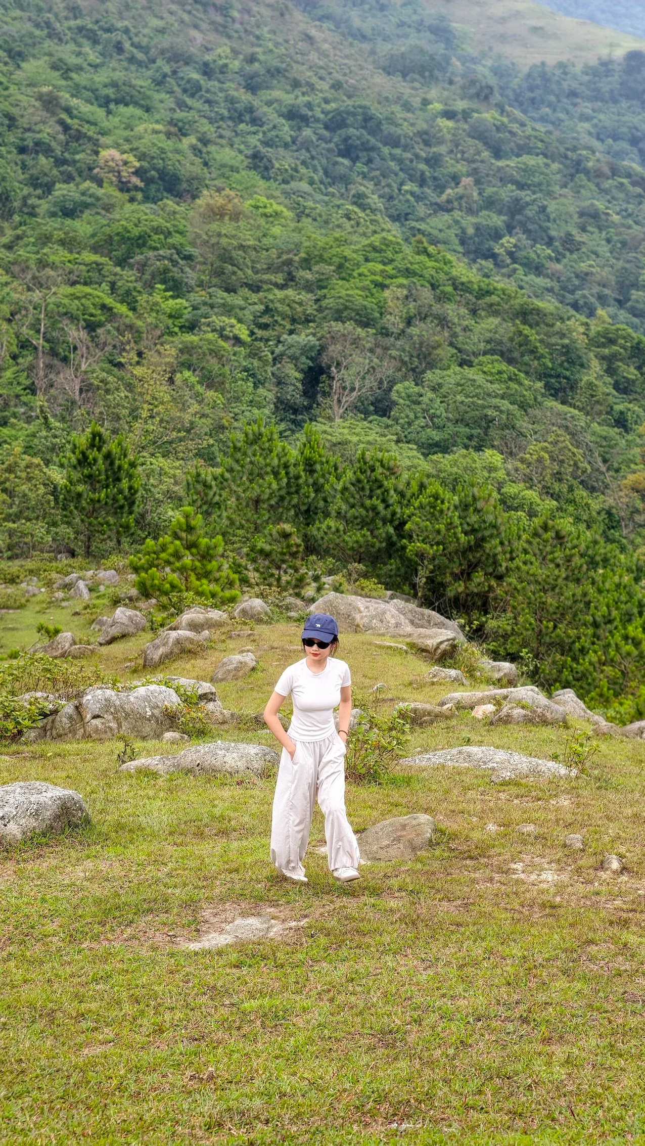 Nữ du khách mặc đồ trắng đứng giữa bãi cỏ Ngọa Vân