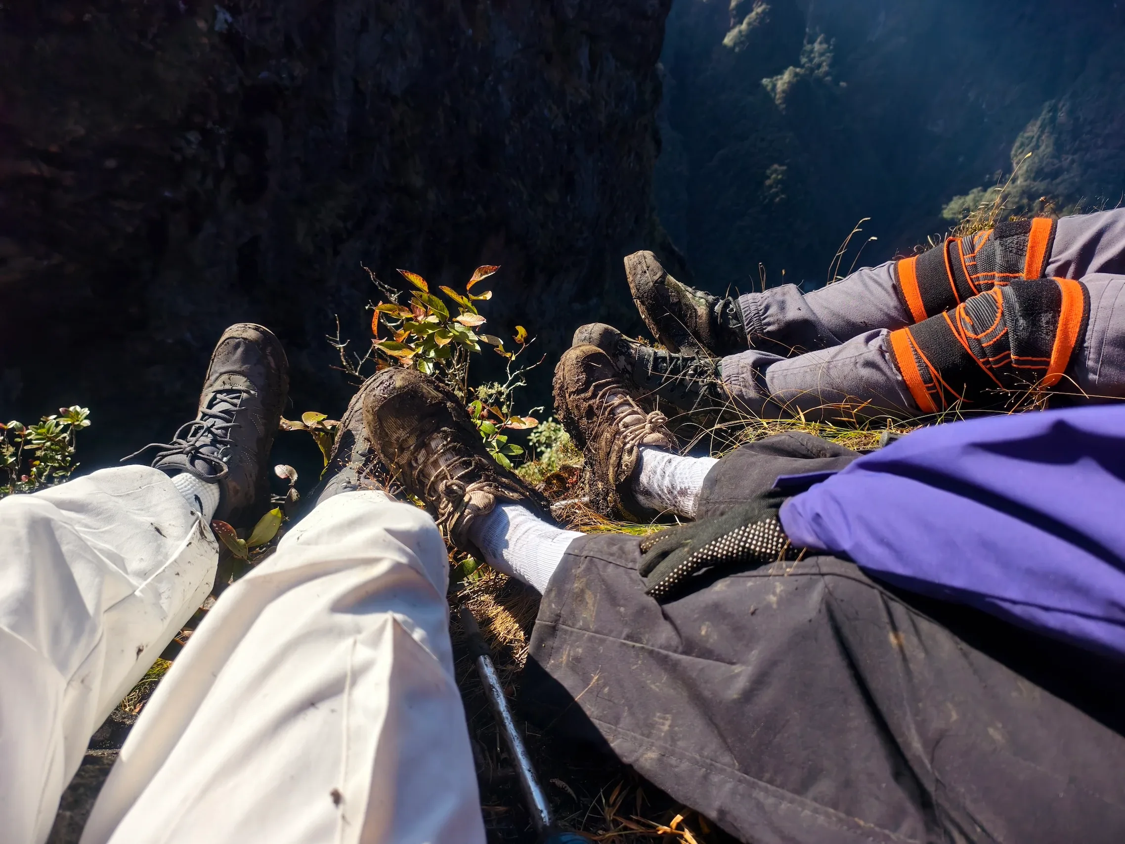 Nhóm trekking nằm nghỉ trên vách đá nhìn xuống thung lũng sâu