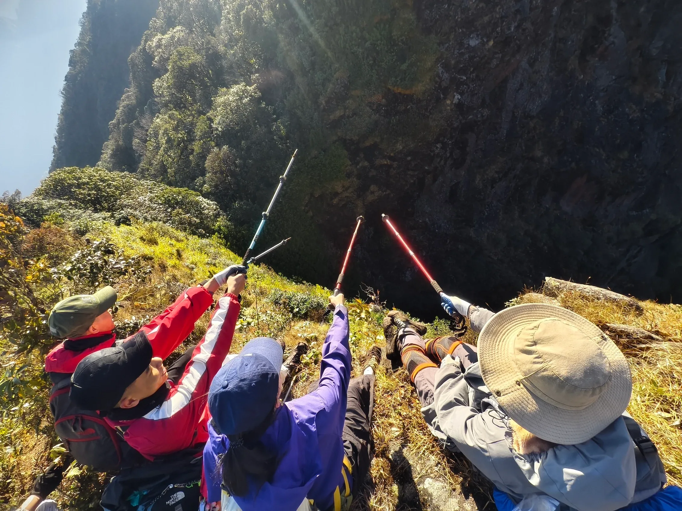 Nhóm trekking ngồi nghỉ và dùng bữa trên sườn núi dốc