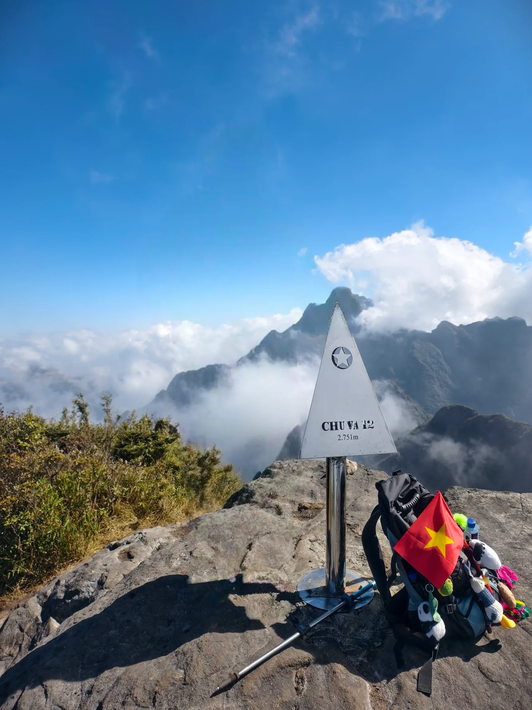 Balo trekking gắn cờ Việt Nam đặt bên cột mốc Chu Va 12 giữa núi mây