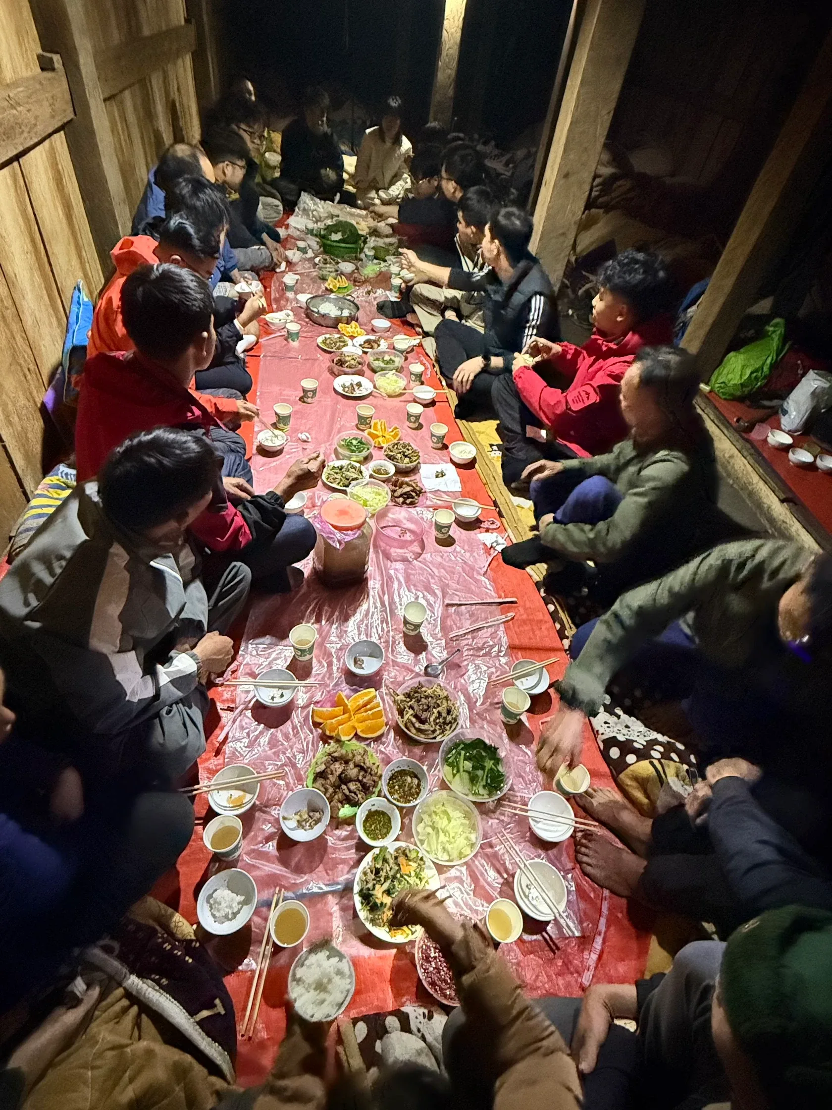 Đoàn trekking quây quần dùng bữa bên bàn dài trong nhà gỗ
