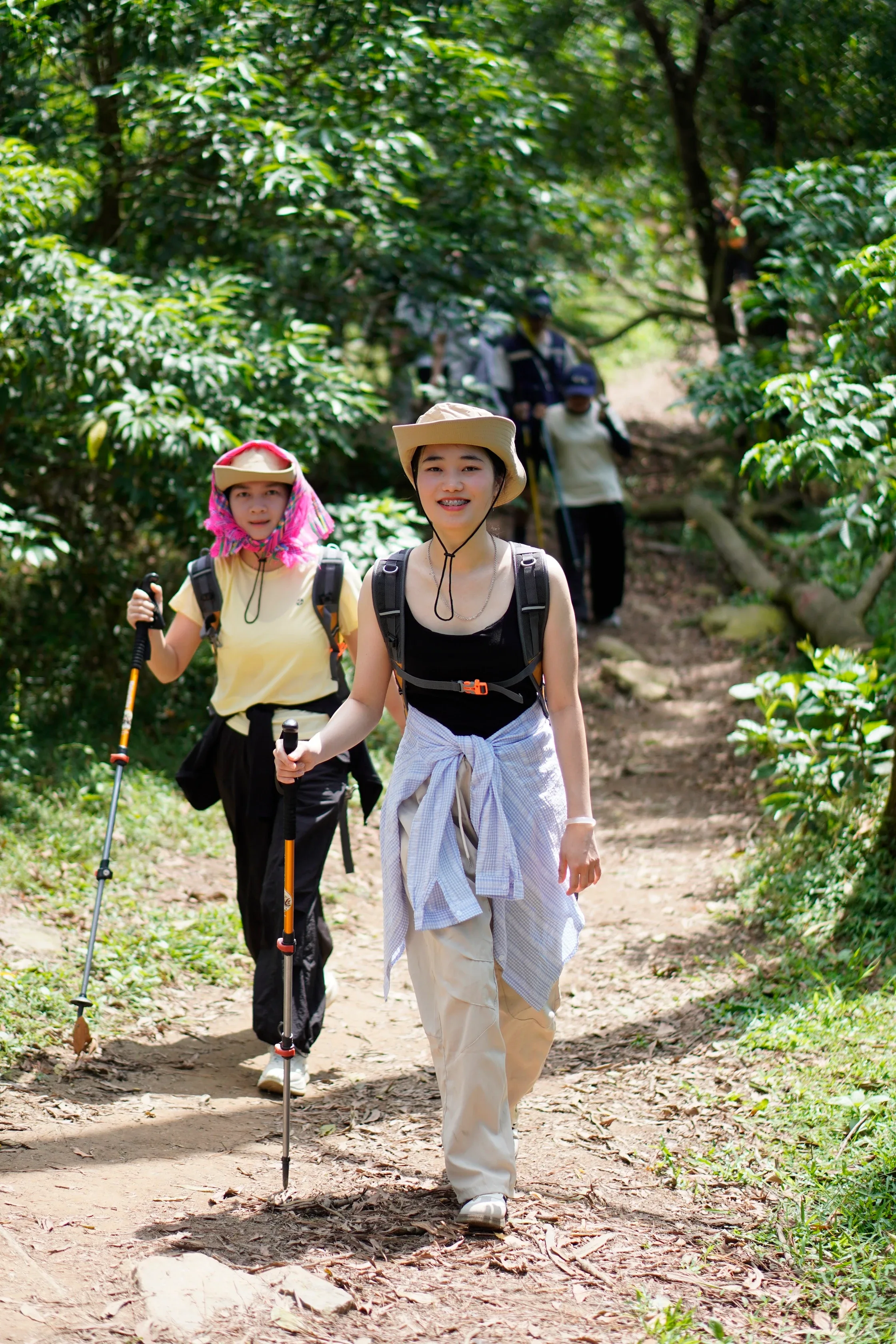 Hai nữ du khách cầm gậy trekking đi trên đường rừng