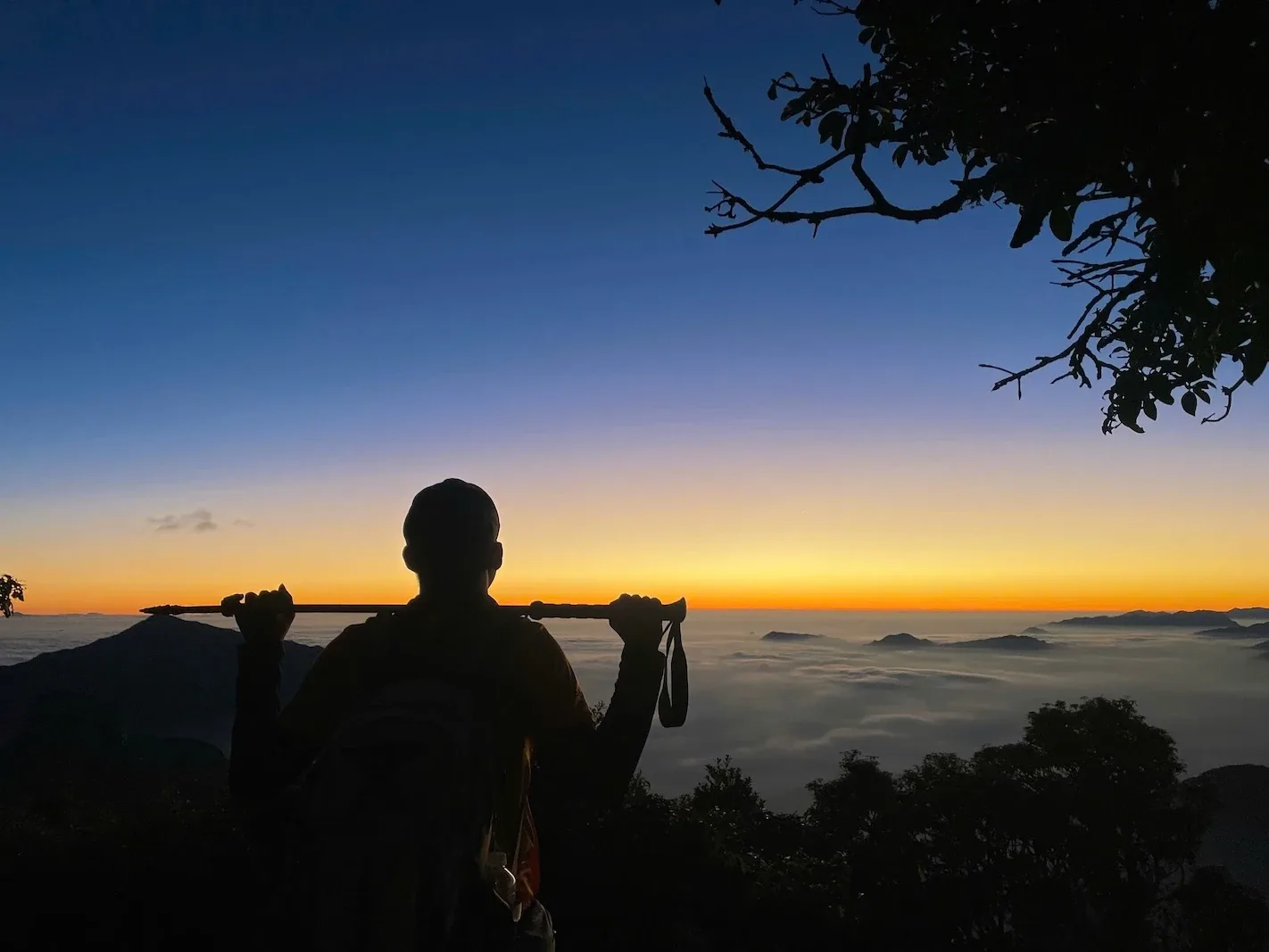 Bóng du khách cầm gậy trekking trước biển mây lúc bình minh
