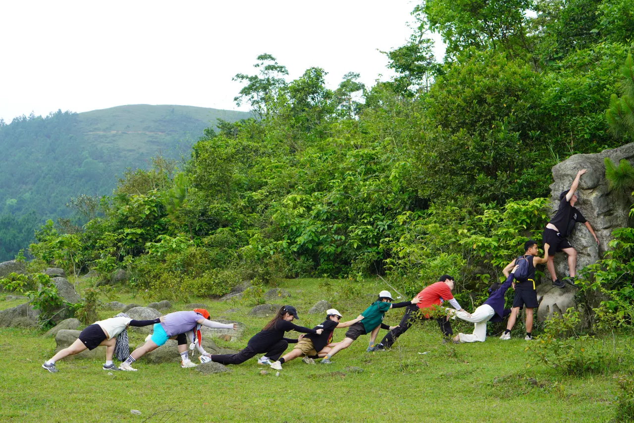 Đoàn khách nối thành hàng dài, cùng nhau trèo qua tảng đá lớn trên đường trekking Ngọa Vân
